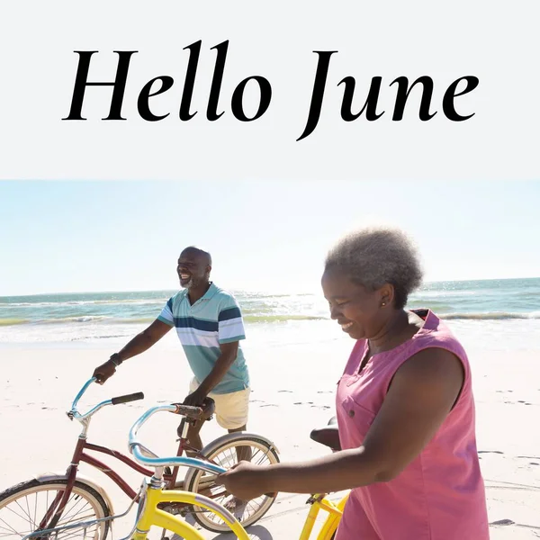 Composition of hello june text over african american senior couple with bikes by seaside. June, summer and vacation concept digitally generated image.