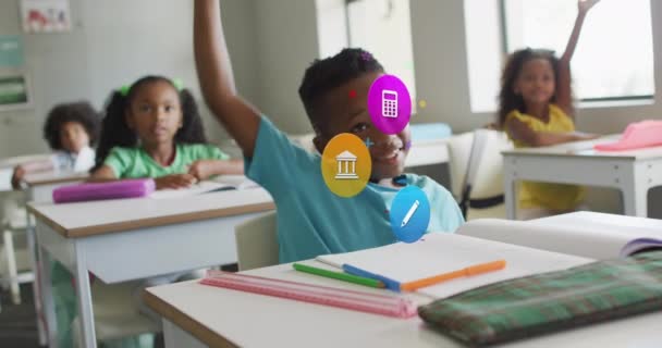 教室の机で手を上げる幸せな多様な学童の上の学校の主題のアイコンのアニメーション 子供時代 デジタルで生成されたビデオ — ストック動画