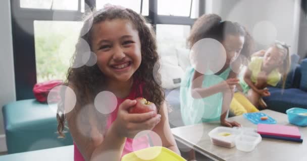 Animation Weißer Bokeh Lichtflecken Über Fröhlichen Schulmädchen Die Lunchpakete Essen — Stockvideo