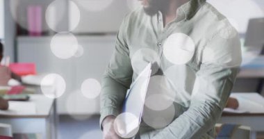 Mutlu Afrika kökenli Amerikalı erkek öğretmenin sınıfta gülümsemesi üzerine ışık noktalarının animasyonu. Okul, öğretmenlik, eğitim ve öğrenme, dijital olarak oluşturulmuş video.