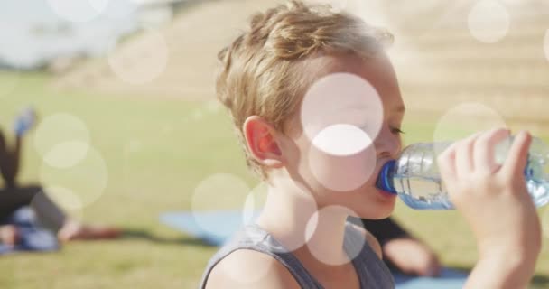 Animering Ljusa Fläckar Över Glada Olika Skolpojkar Dricksvatten Utomhus Yoga — Stockvideo