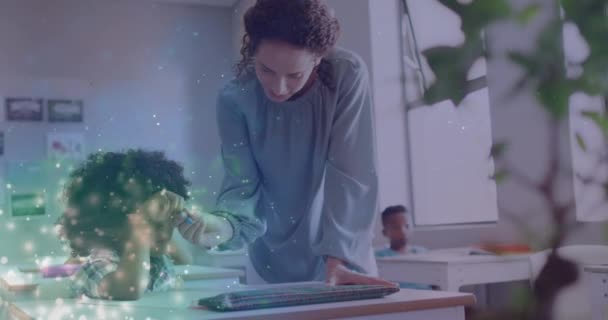 教室で机の上で学童を助ける幸せな多様な女性教師の上に光粒子のアニメーション 子供時代 デジタルで生成されたビデオ — ストック動画