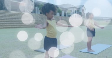 Açık havada yoga yaparken mutlu çeşitliliğin üzerinde beyaz ışık lekelerinin animasyonu. Sağlık, refah, okul, eğitim, çocukluk ve öğrenme, dijital olarak üretilen video.