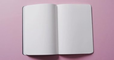 Pembe arka planda fotokopi alanı olan boş kitabı yavaş çekimde kapat. Edebiyat, okuma ve kitaplar.