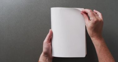 El yapraklarını kitabın içinde gri arkaplanlı fotokopi alanı ile yavaş çekimde kapat. Edebiyat, okuma, boş zaman ve kitaplar..