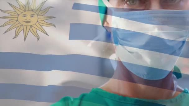 Animação Acenar Bandeira Uruguai Contra Cirurgiã Caucasiana Máscara Cirúrgica Hospital — Vídeo de Stock