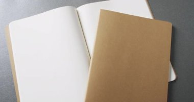 Açık boş kitap ve kahverengi defterin arka planında gri arkaplanı yavaş çekimde kopyala. Edebiyat, okuma ve kitaplar.