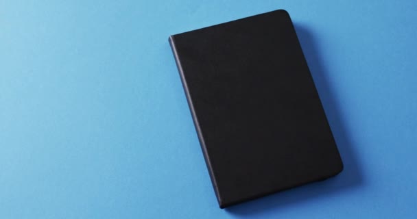Nahaufnahme Eines Geschlossenen Schwarzen Buches Mit Kopierraum Auf Blauem Hintergrund — Stockvideo