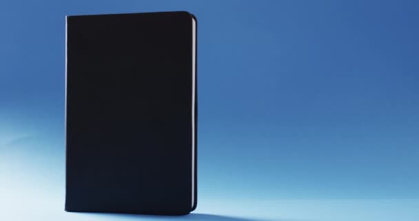 Крупним Планом Закрита Чорна Книга Стоїть Вертикально Копіювальним Простором Синьому — стокове відео