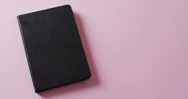 Close Closed Black Book Copy Space Pink Background Slow Motion — Stock Video