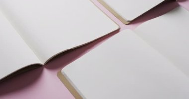 Pembe arka planda fotokopi alanı olan boş kitapları yavaş çekimde kapat. Edebiyat, okuma ve kitaplar.