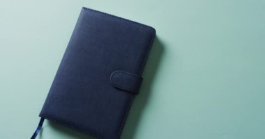 Kapalı mavi defterin üzerinde yeşil arkaplan olan kopyasını yavaş çekimde kapat. Boş zaman, okuma ve kitap okuma..