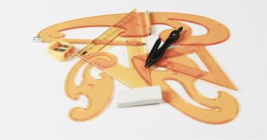 Pusulayı, kalemi, bileyiciyi, silgiyi ve cetvelleri beyaz arka planda, yavaş çekimde kapatın. Geometri, tasarım, öğrenme ve eğitim kavramı.