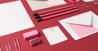 Kalemleri, kalemleri ve kırtasiyeleri kırmızı arka planda yavaş çekimde kapat. Masa, iletişim, çalışma alanı, kırtasiye ve düzen kavramı.