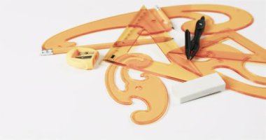 Pusulayı, kalemi, bileyiciyi, silgiyi ve cetvelleri beyaz arka planda, yavaş çekimde kapatın. Geometri, tasarım, öğrenme ve eğitim kavramı.