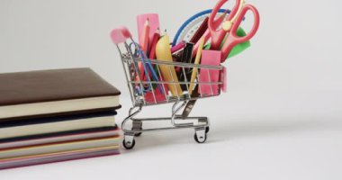 Okul eşyaları ve gri arkaplanlı kitaplarla alışveriş arabalarını kapatın. Okuma, öğrenme, okul ve eğitim kavramı.