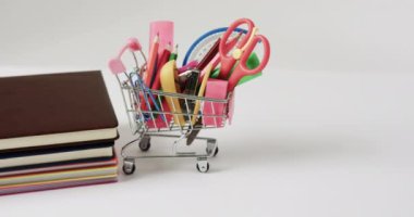 Okul eşyaları ve gri arkaplanlı kitaplarla alışveriş arabalarını kapatın. Okuma, öğrenme, okul ve eğitim kavramı.