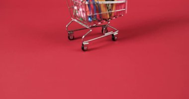 Kırmızı arka planda kopya alanı olan okul eşyalarıyla alışveriş arabalarını kapatın. Kırtasiye, öğrenim, okul ve eğitim kavramı.