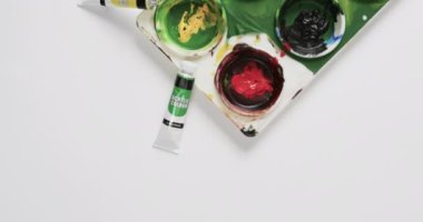 Boyaların ve fırçaların beyaz arkaplandaki görünümü fotokopi alanı ile, yavaş çekimde. Kırtasiye, yaratıcılık, öğrenme, okul ve eğitim kavramı.