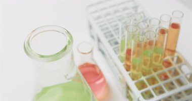 Test tüpleri beyaz arka planda duran mataralarda renkli sıvılar, yavaş çekim. Bilim, kimya, öğrenme, araştırma, laboratuvar, okul ve eğitim kavramı.