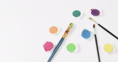 Beyaz arkaplandaki boyaları ve fırçaları fotokopi aletiyle yavaş çekimde kapatın. Kırtasiye, yaratıcılık, öğrenme, okul ve eğitim kavramı.