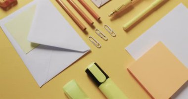 Kalemleri, kâğıtları ve kâğıtları sarı arka planda yavaş çekimde kapat. Masa, iletişim, çalışma alanı, kırtasiye ve düzen kavramı.