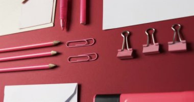 Kalemleri, kalemleri ve kırtasiyeleri kırmızı arka planda yavaş çekimde kapat. Masa, iletişim, çalışma alanı, kırtasiye ve düzen kavramı.