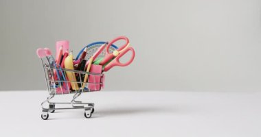 Okul eşyalarıyla alışveriş vagonunu kapat ve gri arka planda fotokopi çektir. Kırtasiye, öğrenim, okul ve eğitim kavramı.