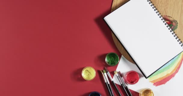 笔记本电脑的俯视图 在红色背景上涂上颜料和刷子 并带有复制空间 动作缓慢 创造力 学校和教育概念 — 图库视频影像