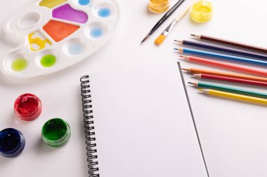 Boyaları, defterleri ve beyaz arkaplanda fotokopi alanı olan fırçaları kapat. Okula dönüş, sanat, resim, okul malzemeleri, öğrenme, okul ve eğitim kavramı.