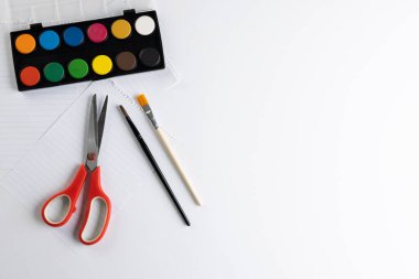 Beyaz arkaplanda fotokopi alanı olan boya, kağıt, makas ve fırçaları kapatın. Okula dönüş, sanat, resim, okul malzemeleri, öğrenme, okul ve eğitim kavramı.