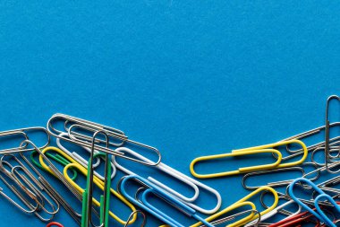 Çok renkli ataç yığınını kapat ve mavi arkaplana kopyala. Okul malzemeleri, organizasyon, öğrenme, okul ve eğitim kavramı.