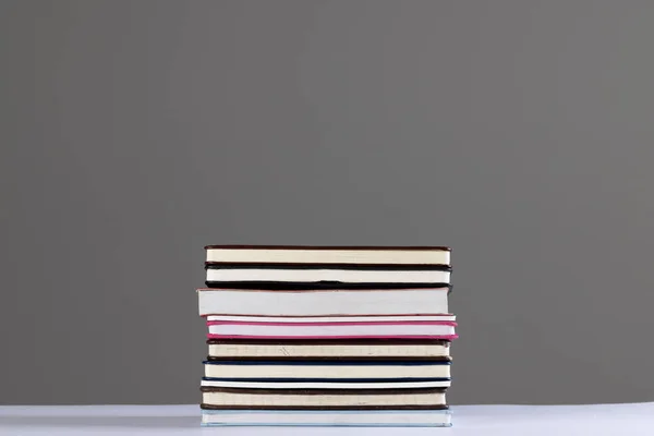 Close up of stack of books and notebooks with copy space on grey background. Reading, learning, school and education concept.
