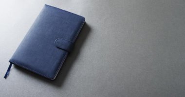 Gri arkaplanı olan mavi defteri yavaş çekimde kapat. Boş zaman, okuma ve kitap okuma..