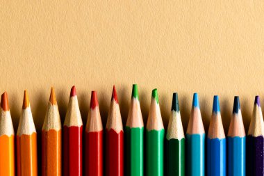 Çok renkli kalemleri kapat ve turuncu arka plandaki boşluğu kopyala. Yazarlık, renklendirme, öğrenme, okul ve eğitim kavramı.