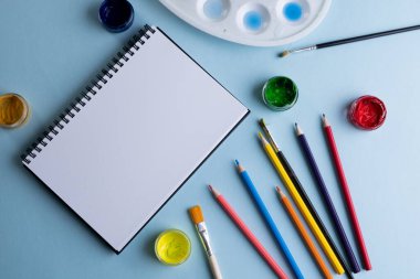 Boya, kalem, defter ve mavi arkaplanda fotokopi alanı olan fırçaları kapat. Okula dönüş, sanat, resim, okul malzemeleri, öğrenme, okul ve eğitim kavramı.