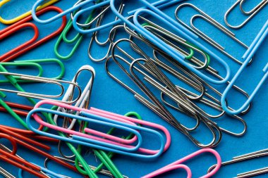 Mavi arkaplanda çok renkli ataç yığınını kapat. Okul malzemeleri, organizasyon, öğrenme, okul ve eğitim kavramı.