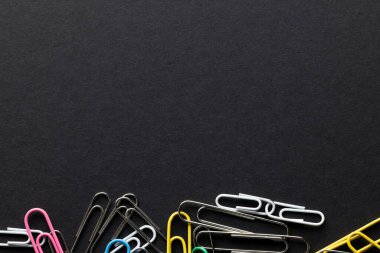 Çok renkli ataç yığınını kapat ve siyah arkaplana kopyala. Okul malzemeleri, organizasyon, öğrenme, okul ve eğitim kavramı.