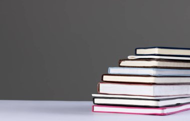 Gri arkaplanda kopya alanı olan kitap ve defterleri kapat. Okuma, öğrenme, okul ve eğitim kavramı.