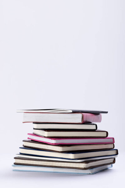 Close up of stack of books and notebooks with copy space on white background. Reading, learning, school and education concept.
