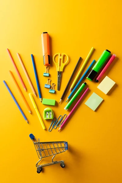 Großaufnahme Eines Miniatur Einkaufswagens Mit Schulmaterialien Auf Orangefarbenem Hintergrund Zurück — Stockfoto