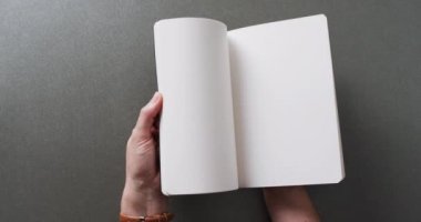 El yapraklarını kitabın içinde gri arkaplanlı fotokopi alanı ile yavaş çekimde kapat. Edebiyat, okuma, boş zaman ve kitaplar..