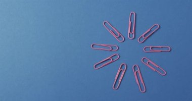 Mavi arkaplanda fotokopi alanı ile yavaş çekimde düzenlenmiş pembe ataçların genel görünümü. Kırtasiye, öğrenim, okul ve eğitim kavramı.