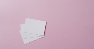 Pembe arka planda fotokopi alanı olan kâğıt parçalarının üzerine ağır çekimde el ele tutuşmak. Doku ve kağıt.