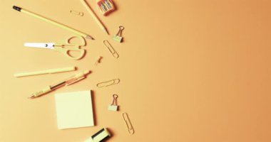 Turuncu arka planda fotokopi alanı olan okul kırtasiyesinin genel görünümü, yavaş çekimde. Kırtasiye, öğrenim, okul ve eğitim kavramı.