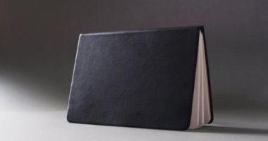 Açık siyah kitabın yatay, gri arkaplanda ise ağır çekimde fotokopi alanı ile kapanmasını istiyorum. Edebiyat, okuma ve kitaplar.