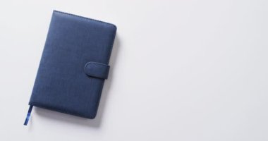 Kapalı mavi defteri beyaz arkaplanda yavaş çekimde kopyalayarak kapat. Boş zaman, okuma ve kitap okuma..