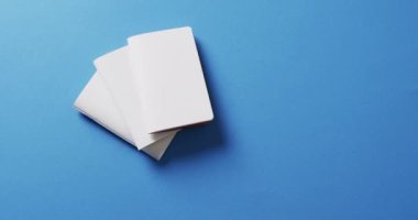 El ele tutuşan kağıt parçalarının üzerinde mavi arka planda fotokopi alanı olan kağıt parçaları ağır çekimde. Doku ve kağıt.