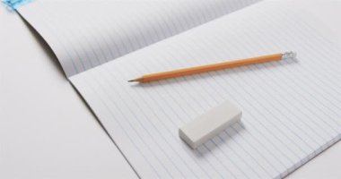 Okul kırtasiyesinin olduğu açık not defterini gri arka planda, yavaş çekimde kapat. Kırtasiye, öğrenim, okul ve eğitim kavramı.