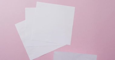 Pembe arka planda fotokopi alanı olan kâğıt parçalarının üzerine ağır çekimde el ele tutuşmak. Doku ve kağıt.